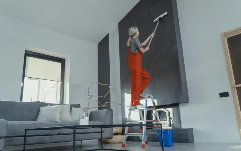 a woman on a ladder cleaning a wall
