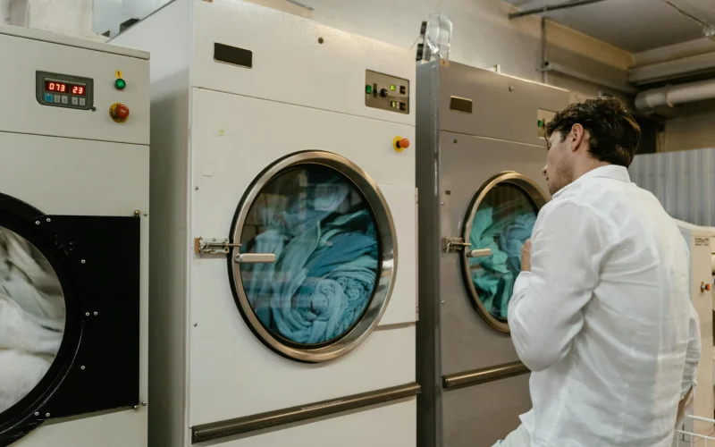 a man in a white shirt and white pants standing next to a washing machine